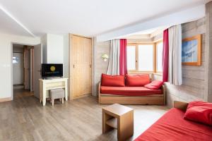 ein Wohnzimmer mit einem roten Sofa und einem Fernseher in der Unterkunft Résidence Le Christiana - maeva Home - Appartement 2 Pièces 7 Personnes - Sélection MAE-5512 in Saint-Bon-Tarentaise