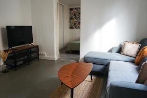 ein Wohnzimmer mit einem blauen Sofa und einem Holztisch in der Unterkunft Maison de ville - Chelles Close to Disney & Paris in Chelles