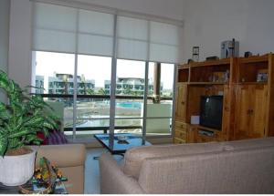 ein Wohnzimmer mit Sofa und Fernseher in der Unterkunft Casa Mccraren Torre 3-302 at Mayan Lakes in Playa Encanto
