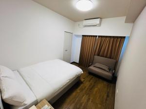 Un pequeño dormitorio con una cama y una silla. en Mr,KINJO in RYCOM Kitanakagusuku - Vacation STAY 59274v, en Shimabuku