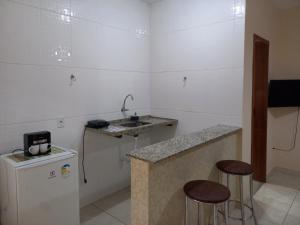 a small kitchen with a sink and two bar stools at Chalé Cipó Maia in Serra do Cipo