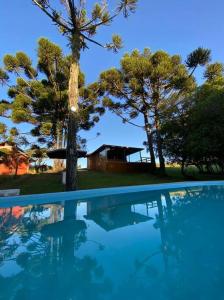 une piscine avec des arbres et une maison en arrière-plan dans l'établissement Chácara.lazer.cxs, à Caxias do Sul