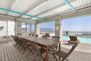 a dining room with a table and chairs and a pool at Sea Spray B104 in Table View