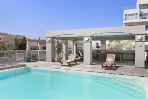 a swimming pool with two chairs and a patio at Sea Spray B104 in Table View