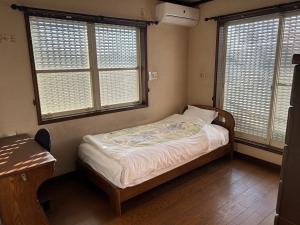 a small bedroom with a bed and two windows at Shin-SHIN-Kakamigahara - Vacation STAY 16114 in Kakamigahara