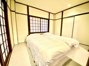 a white bed in a room with windows at Geku-mae Bettei Hoshiori - Vacation STAY 65143v in Ise