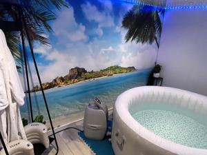 ein Badezimmer mit einer Badewanne und einem Gemälde vom Strand in der Unterkunft Sparadisejacuzzi in Éragny