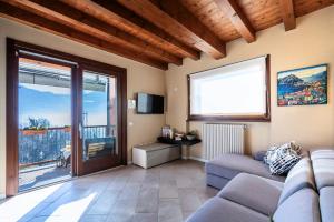 - un salon avec un canapé et une grande fenêtre dans l'établissement Iseo Lake Villa con vista lago e piscina, à Costa Volpino