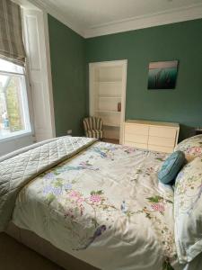 a bedroom with a bed with a floral bedspread at Luxury Apartment at Barron House in Nairn