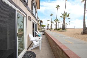 a building with two white chairs on a sidewalk next to the beach at Updated Home on the Boardwalk with Private Rear Unit in Newport Beach
