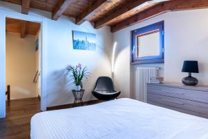 a bedroom with a white bed and a chair at Iseo Lake Villa con vista lago e piscina in Costa Volpino