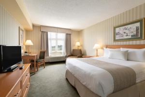 a hotel room with a bed and a flat screen tv at Days Inn by Wyndham Orillia in Orillia