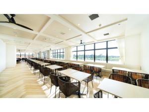 uma cafetaria com mesas, cadeiras e janelas em Hotel Torifito Miyakojima Resort - Vacation STAY 79484v em Ilhas Miyako