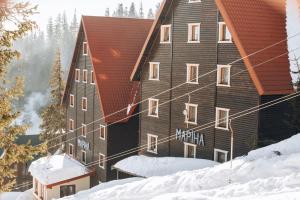 a large wooden building with snow in front of it at Маріна Драгобрат in Dragobrat +142 photos