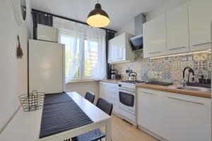 a kitchen with white appliances and a table with chairs at Apartament Dzień Dobry 2 in Wałbrzych