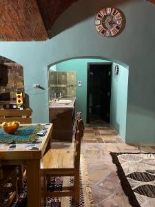 cocina con mesa y reloj en la pared en Nubian Magic villa, en Nag` el-Ramla