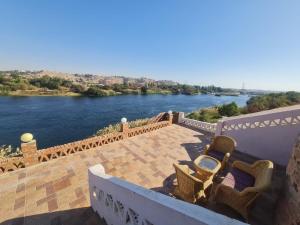 balcón con sillas y vistas al río en Nubian Magic villa, en Nag` el-Ramla