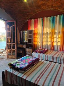 Habitación con 2 camas y cortina colorida en Nubian Magic villa, en Nag` el-Ramla