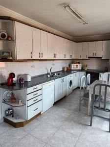 cocina con armarios blancos, fregadero y lavavajillas en Casa Pureza, en Aliaga