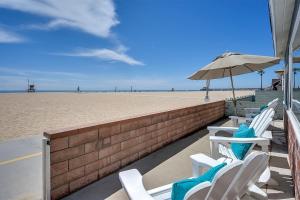 eine Reihe von Stühlen und einem Sonnenschirm am Strand in der Unterkunft TWO BEACHFRONT BUNGALOWS ON THE SAND IN Newport Beach in Newport Beach