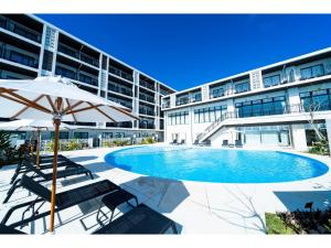 un grand bâtiment avec une piscine et un parasol dans l'établissement Hotel Torifito Miyakojima Resort - Vacation STAY 79471v, à Île Miyako