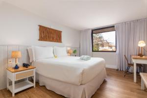 a bedroom with a large white bed and a window at Hotel Aretê in Búzios