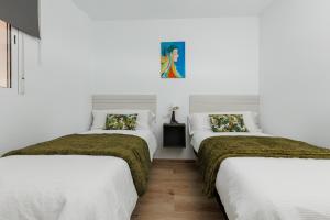 3 camas en una habitación con paredes blancas en Casa Carmen, en Málaga