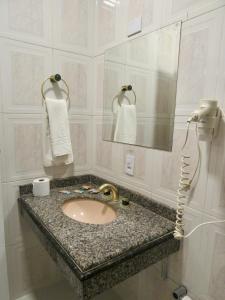 a white bathroom with a sink and a phone at Hotel Estoril Garden & Restaurante in Registro