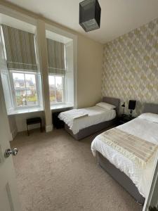a bedroom with two beds and two windows at Luxury Apartment at Barron House in Nairn