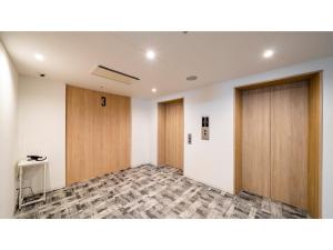una stanza vuota con due porte in legno e un tavolo di Hotel Torifito Miyakojima Resort - Vacation STAY 79479v a Miyakojima