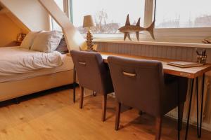 um quarto com uma secretária, uma cama e uma janela em B&B Zee-en-Zo em Noordwijk