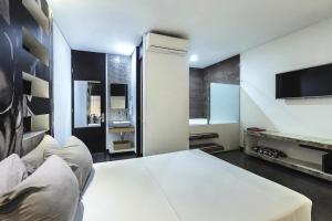 a bedroom with a white bed and a tv at Hotel Medellin Art in Medellín