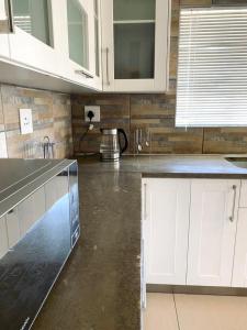 a kitchen with white cabinets and a concrete floor at Spacious Private room in Windhoek