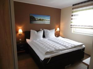 Un dormitorio con una gran cama blanca con ventana. en Villa Lago am Fleesensee, en Göhren-Lebbin