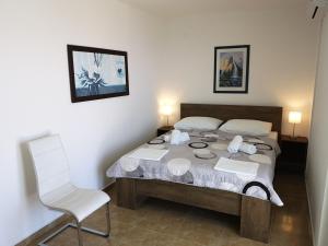a bedroom with a bed and a white chair at Apartmani Anda in Živogošće