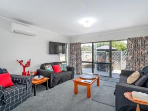 a living room with two couches and a table at Beach Life - Whangamata Holiday Home in Whangamata
