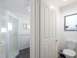 a bathroom with a toilet and a glass door at Beach Life - Whangamata Holiday Home in Whangamata +8 photos
