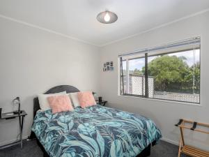 a bedroom with a bed and a window at Beach Life - Whangamata Holiday Home in Whangamata