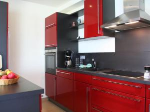a kitchen with red cabinets and a bowl of fruit at Strandhus Sellin - House 1 in Ostseebad Sellin