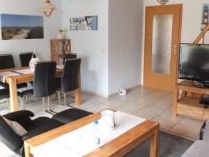 Una sala de estar con una mesa y sillas y un televisor. en Holiday home Kaptain's bunk, en Carolinensiel