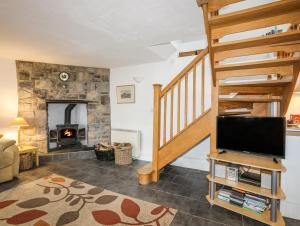 a living room with a staircase and a fireplace at Beech Tree Cottage in Caernarfon