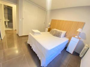 Schlafzimmer mit einem weißen Bett mit einem Kopfteil aus Holz in der Unterkunft Depto Nueva Cordoba Guemes in Cordoba