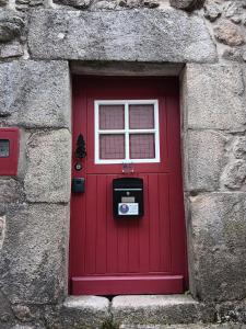 a red door with a window in a stone wall at Recanto da Pedra in Linhares