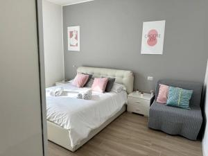 een slaapkamer met een bed met roze kussens en een stoel bij [Monza Centro in 10 Min]Comfort Suite XL in Monza