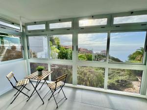 a room with a table and chairs and large windows at Mar & Teide in Sauzal