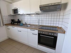 cocina con armarios blancos y fogones en House beach holidays "above", en Wangerland