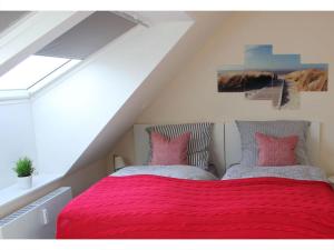 een slaapkamer met een rood bed met 2 kussens bij Cosy apartment near centre in Langeoog