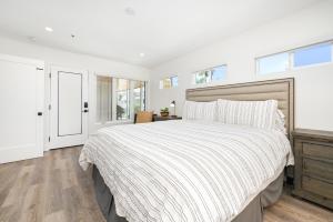 a white bedroom with a large bed and windows at 4 bedroom Renovated Home on Balboa Island in Newport Beach