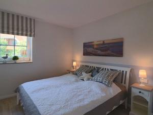 a bedroom with a white bed with two lamps and a window at Holiday apartment SeaSide in Westerbergen