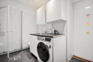 een wasmachine in een badkamer met een wastafel bij House with iconic view in Tromsø